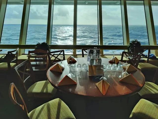 A dining table set beside a window overlooking the water