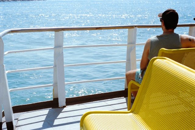 A solo traveler looking out across the ocean from a ferry deck